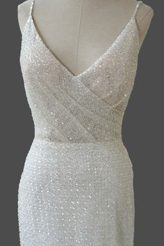 the back of a white dress with sequins on it and a mannequin head