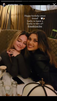 two beautiful women hugging each other in front of a table with candles and wine glasses