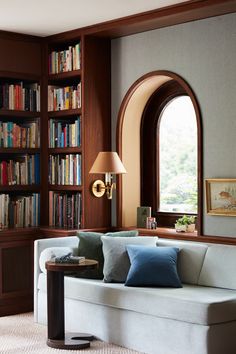 a living room filled with furniture and a book shelf next to a window covered in books