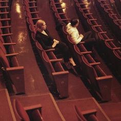 two women sitting in rows of empty seats