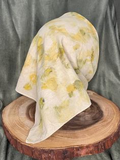 a white and yellow flowered hat sitting on top of a piece of wood