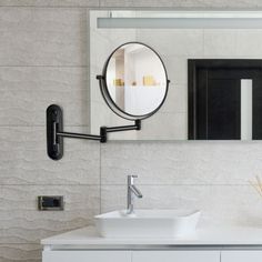 a bathroom sink sitting under a mirror in front of a wall mounted faucet