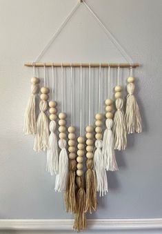 a wall hanging made out of wood beads and tassels on a white wall