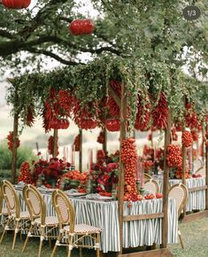 an outdoor dining area with tables and chairs covered in red flowers, lanterns and paper lanterns