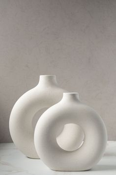 two white vases sitting on top of a table