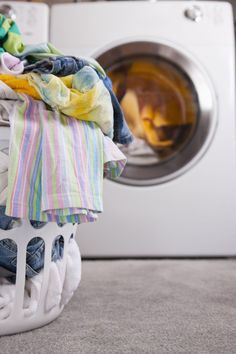 a stack of clothes sitting next to a dryer in front of a washing machine