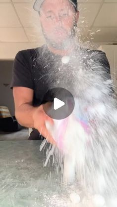 a man is sprinkling water on his face in the middle of a room