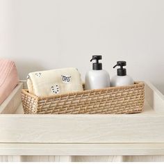 a basket with soap, lotion and hand sanitizers in it on a table