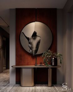 a round mirror hangs on the wall next to a table with a plant in it