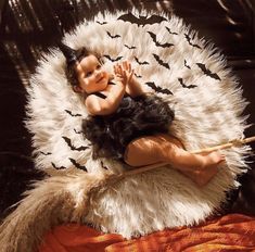 a baby laying on top of a white and black animal rug with bats around it