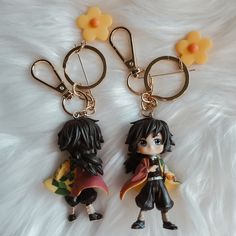 two keychains with anime characters on them sitting on a white furnishing