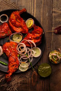 grilled chicken with onions, peppers and limes on a black plate next to dipping sauce