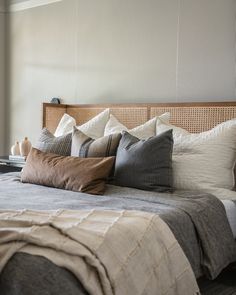 a bed with many pillows on top of it and a window in the back ground