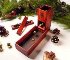 an open wooden box sitting on top of a table next to pine cones and christmas decorations