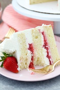 a slice of strawberry layer cake on a pink plate with a gold fork next to it