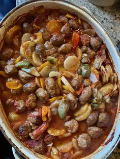 a pan filled with meatballs and vegetables on top of a table