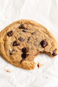 a chocolate chip cookie with one bite taken out and the rest of it's half eaten