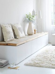 a white room with pillows and vases on the window sill