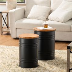 two black barrel tables sitting on top of a rug in front of a white couch