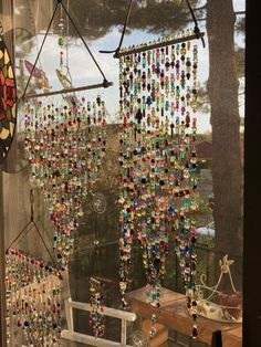 there are many beads hanging on the window and in front of it is a wind chime