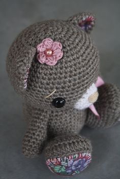 a crocheted teddy bear with a pink flower on it's head and ears