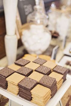 a table topped with cookies and crackers on top of a white cake plate covered in chocolate