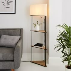 a living room with a couch, chair and lamp on the floor next to a potted plant