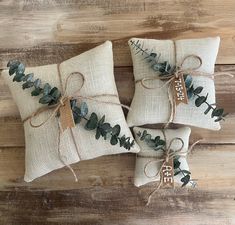 three pillows with green leaves tied to them on a wooden floor next to each other