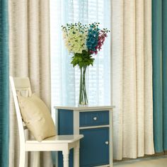 a vase filled with flowers sitting on top of a table next to a chair and window