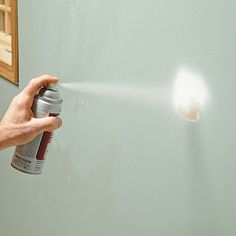 a person spraying paint on the wall with a spray can