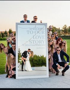 a group of people posing for a photo in front of a large sign with the words welcome to our love story written on it