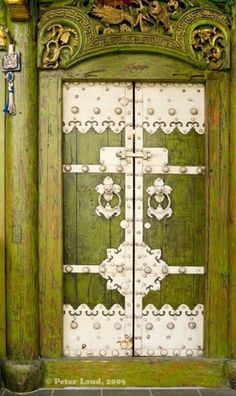 an old wooden door with ornate carvings on the front and side panels, painted green