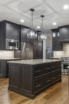 a large kitchen with dark wood cabinets and stainless steel appliances, along with hardwood flooring