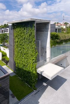 a house covered in green plants and sitting on top of a roof with a bench next to it