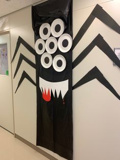 an office hallway decorated in black and white paper with spider decorations on the front door