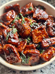 a white bowl filled with meat covered in sauce