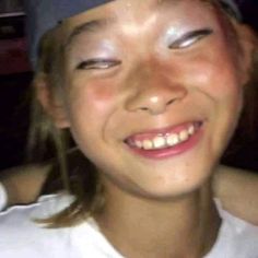 a close up of a person wearing a baseball cap and smiling at the camera with her eyes closed