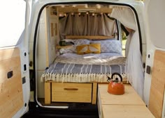 the interior of a camper van with its door open and bed in the back