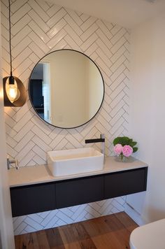 a bathroom with a round mirror above the sink and a black counter top under it