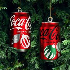 two coca cola christmas ornaments hanging from a tree