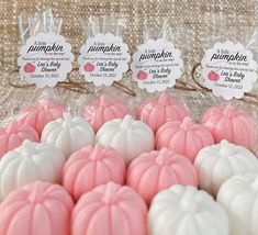 pink and white pumpkins are on display in plastic bags with tags attached to them