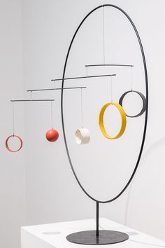 an art piece with three circles hanging from it's sides and two rings on each side