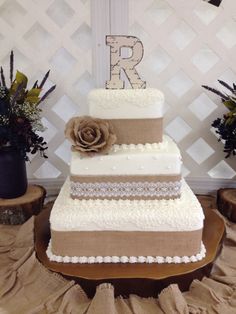 a three tiered wedding cake with flowers on the top and initials on the side