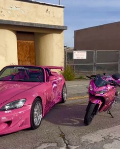 two pink sports cars parked next to each other in front of a building on the street