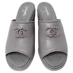 Introducing the Chanel 2016 Grey Quilted Lambskin Interlocking CC Logo Mule Wedge Slides, a luxurious blend of comfort and timeless elegance. Crafted from sumptuous quilted lambskin in a chic grey hue, these slides are elevated by a signature interlocking CC logo at the center. The logo is artfully composed of leather and interwoven silver-tone chain, adding a touch of refined sophistication and classic Chanel charm. These versatile mules can easily transition from casual outings to more formal Chanel Charm, Chanel Maxi, Chanel 2016, Wedge Slides, Classic Chanel, White Trousers, Cc Logo, Black Top, Effortlessly Chic