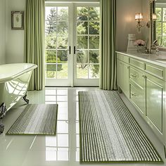 a bathroom with green walls and white flooring next to a bathtub in front of a large window