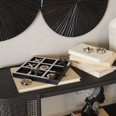 a black table topped with books and rings on top of each other next to a vase