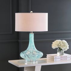 a blue glass lamp sitting on top of a table next to a white vase with flowers