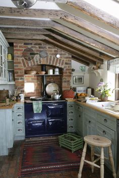 an old fashioned kitchen with blue stove and wooden stools in the middle of it