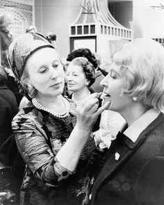 black and white photograph of two women brushing each other's teeth at an event